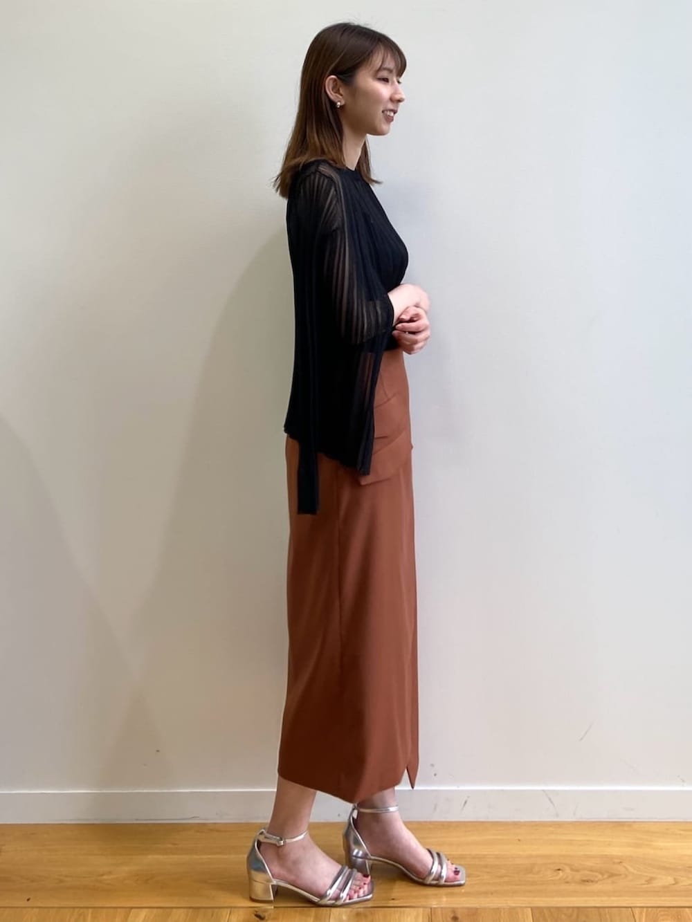 ブラウン系のスカート、シルバー系のサンダル、ブラック系のニット/セーターを着用したレディースの春コーディネートの3枚目の写真
