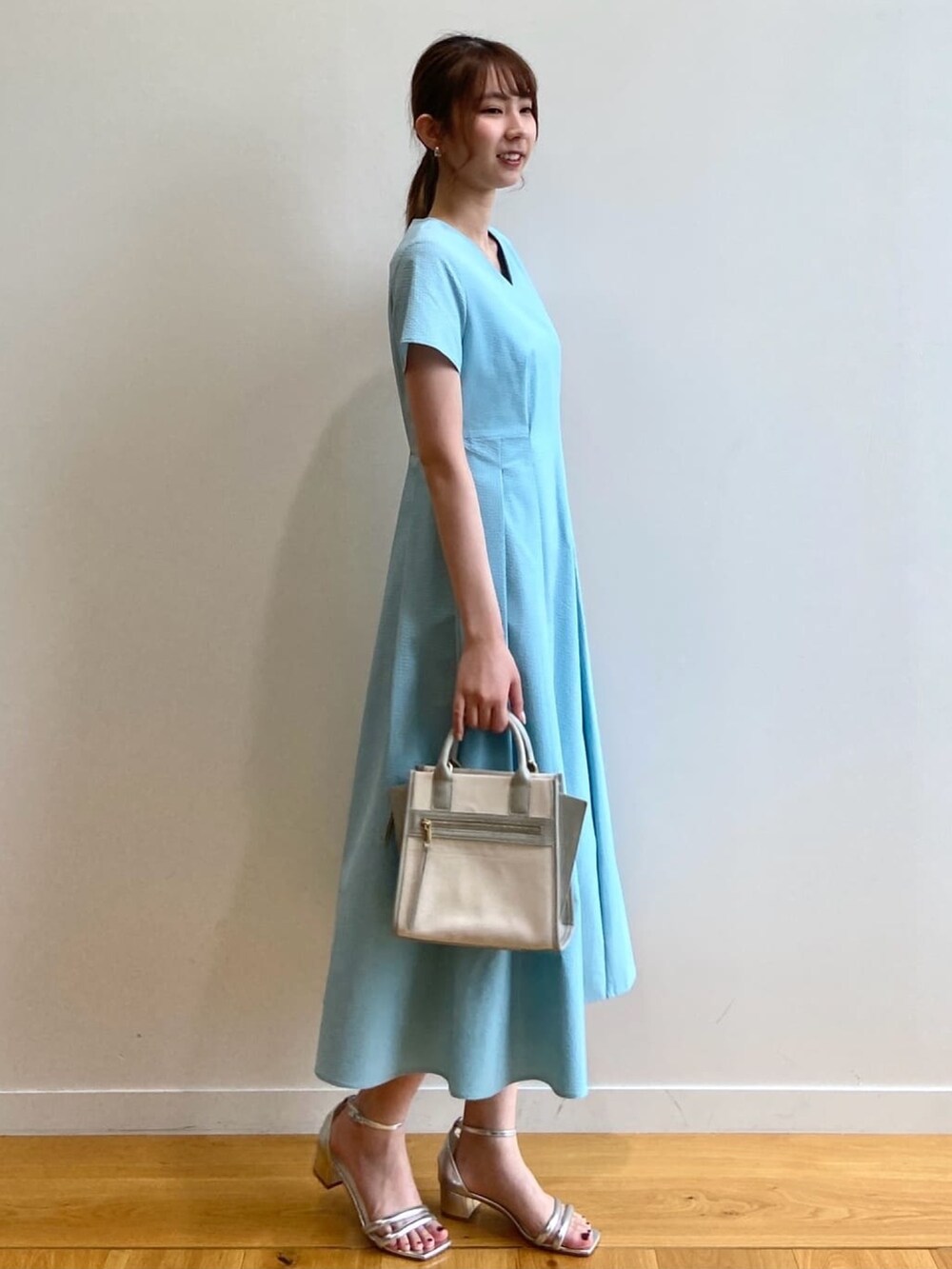 ブルー系のワンピース、シルバー系のサンダル、グレー系のハンドバッグを着用したレディースの夏コーディネートの3枚目の写真