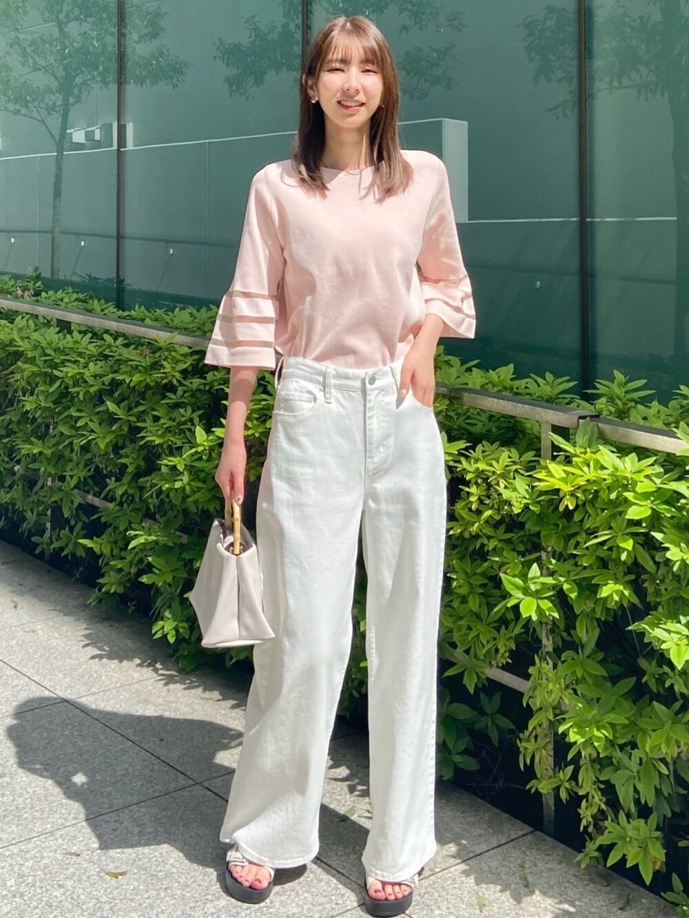 ピンク系のニット/セーター、ホワイト系のデニムパンツ、ホワイト系のサンダルを着用したレディースの春コーディネートの3枚目の写真