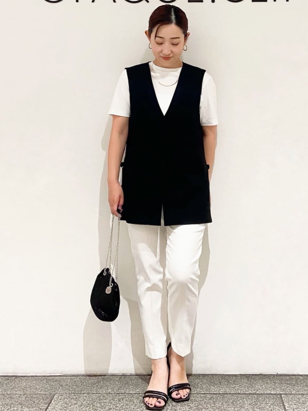 ホワイト系のTシャツ/カットソー、ブラック系のベスト、ブラック系のショルダーバッグを着用したレディースの夏コーディネートの3枚目の写真