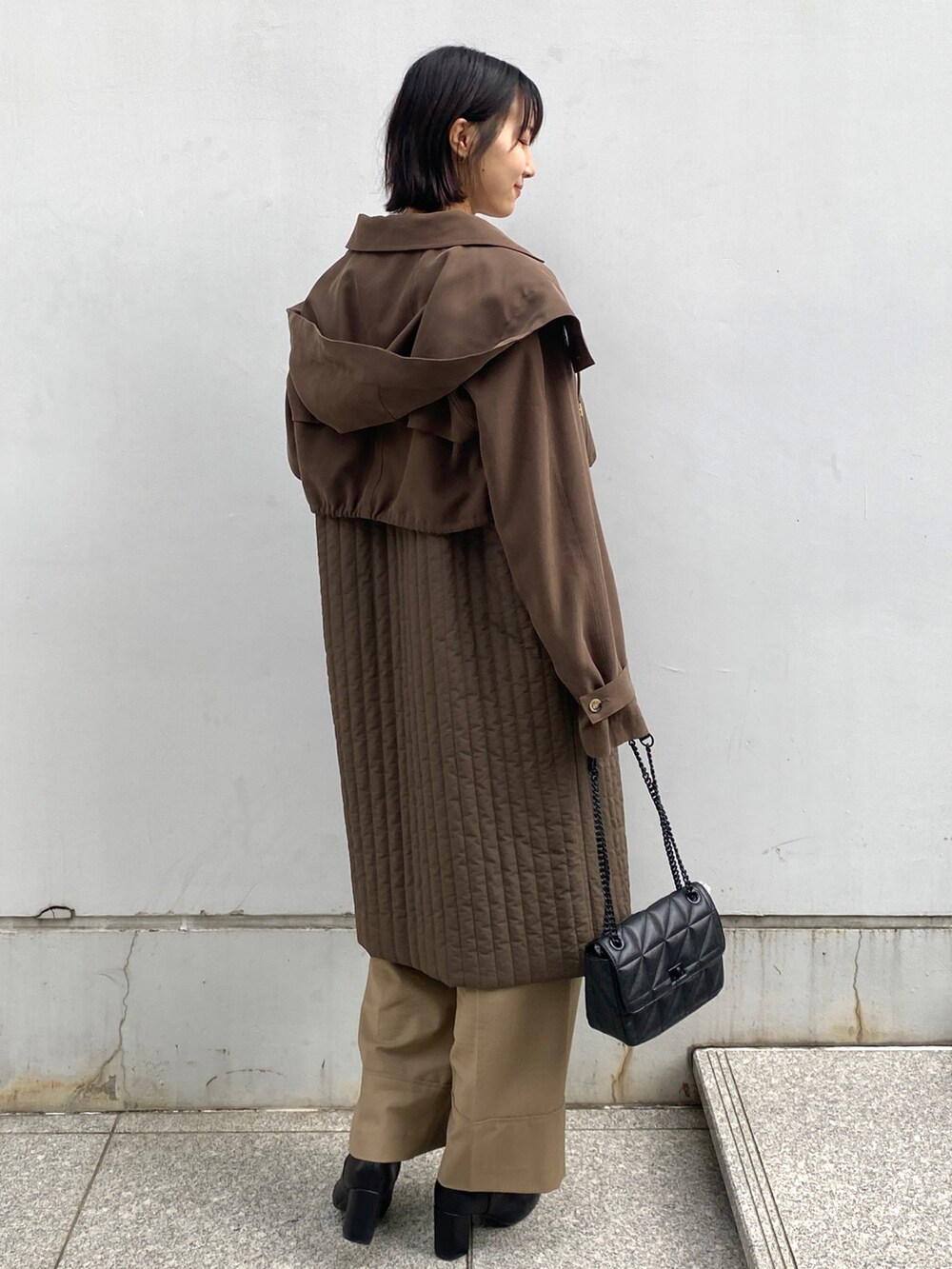 グリーン系のトレンチコート、ベージュ系のその他パンツ、ブラック系のショルダーバッグを着用したレディースの秋コーディネートの2枚目の写真