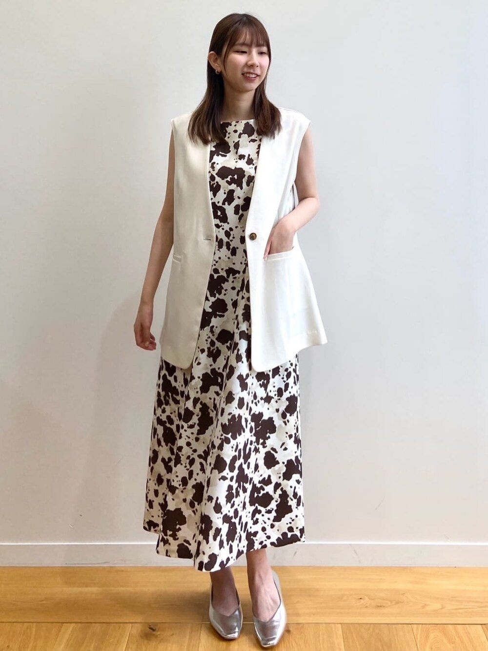 ブラウン系のワンピース、ベージュ系のベスト、シルバー系のパンプスを着用したレディースの夏コーディネートの2枚目の写真