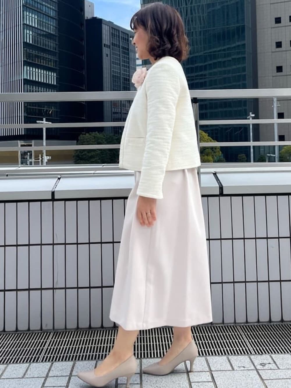 ホワイト系のノーカラージャケット、ベージュ系のワンピース、ベージュ系のパンプスを着用したレディースの冬コーディネートの2枚目の写真