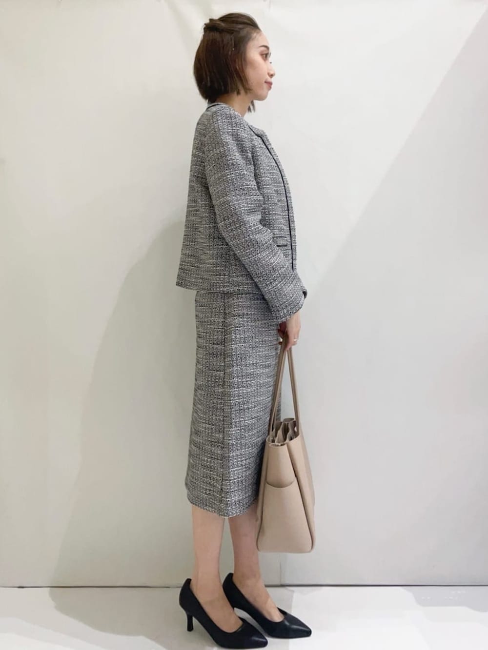 ブラック系のスカート、ブラック系のパンプス、ベージュ系のトートバッグを着用したレディースの冬コーディネートの2枚目の写真