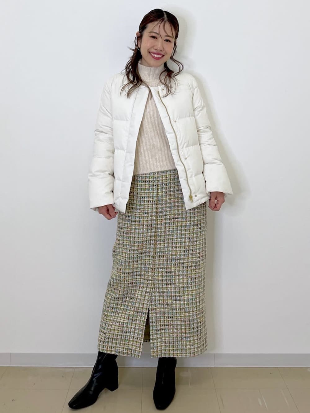 グリーン系のスカート、ホワイト系のダウンジャケット/コート、ホワイト系のニット/セーターを着用したレディースの冬コーディネートの2枚目の写真