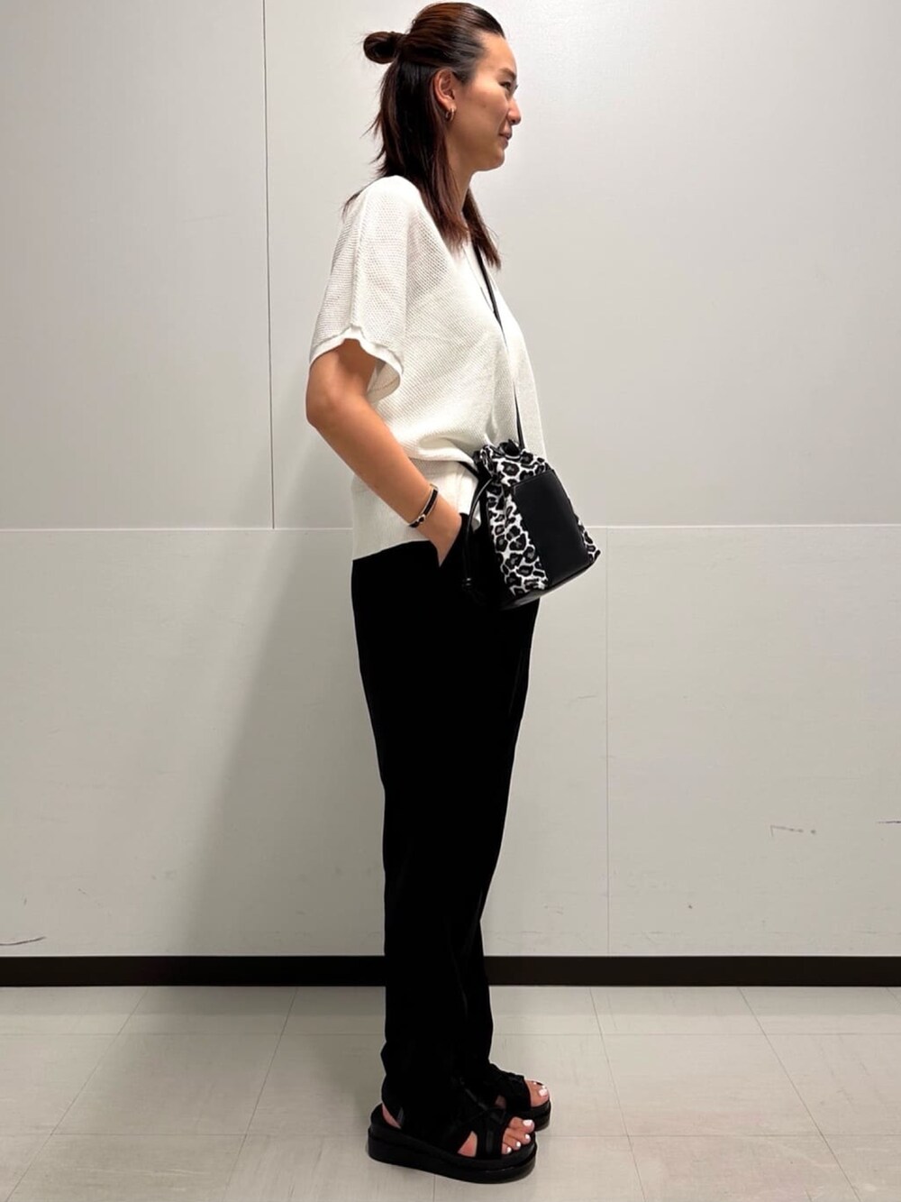 ホワイト系のショルダーバッグ、ブラック系のその他パンツ、ブラック系のサンダルを着用したレディースの夏コーディネートの2枚目の写真