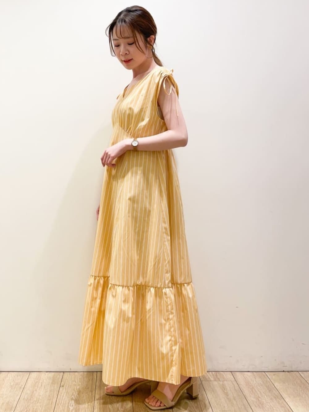 オレンジ系のワンピース、ホワイト系のカーディガン/ボレロ、シルバー系のトートバッグを着用したレディースの春コーディネートの2枚目の写真