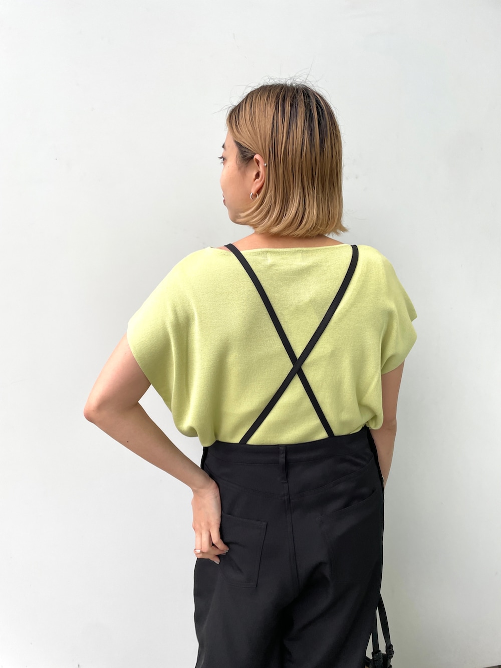 グリーン系のニット/セーター、ブラック系のサロペット/オーバーオール、ブラック系のトートバッグを着用したレディースの夏コーディネートの4枚目の写真