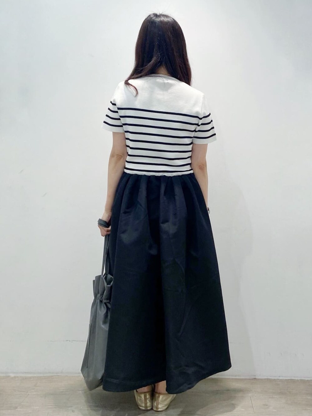 グレー系のトートバッグ、ブラック系のワンピース、ゴールド系のその他シューズを着用したレディースの夏コーディネートの6枚目の写真