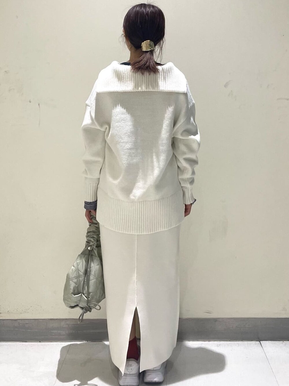 ホワイト系のスカート、ホワイト系のニット/セーター、グリーン系のショルダーバッグを着用したレディースの冬コーディネートの2枚目の写真