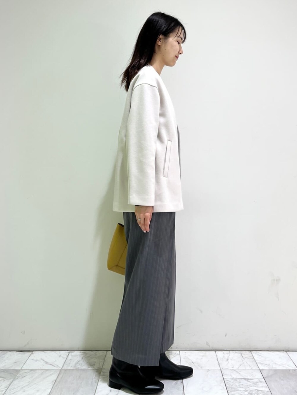 ブラック系のニット/セーター、ホワイト系のノーカラーコート、グレー系のその他パンツを着用したレディースの冬コーディネートの2枚目の写真
