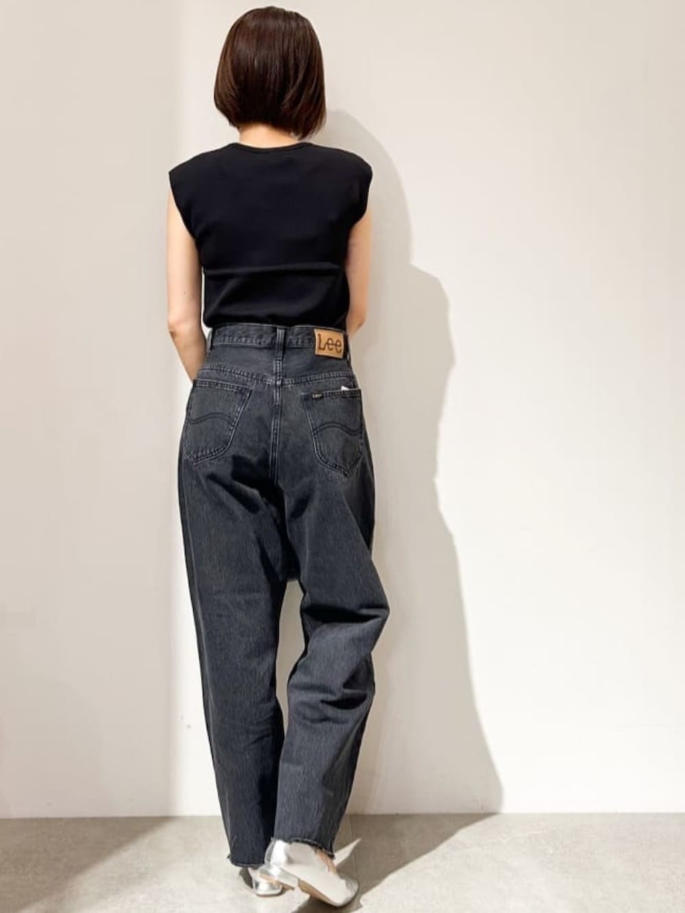 ブラック系のニット/セーター、グレー系のデニムパンツ、シルバー系のパンプスを着用したレディースの夏コーディネートの5枚目の写真