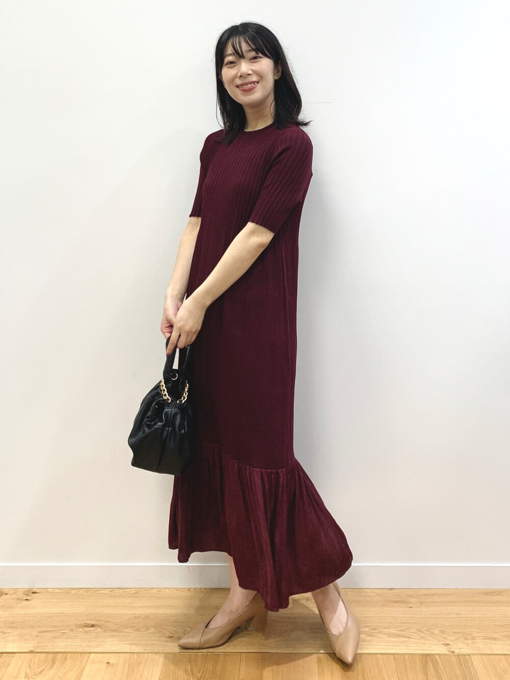 レッド系のワンピース、ブラック系のハンドバッグ、ベージュ系のパンプスを着用したレディースの夏コーディネートの2枚目の写真