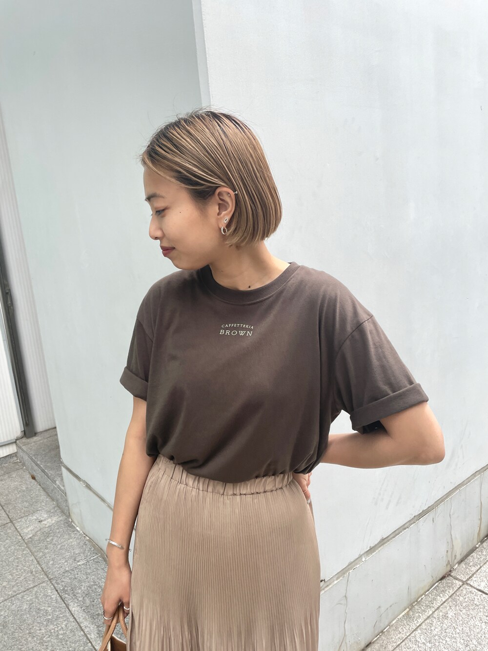 ブラウン系のTシャツ/カットソー、イエロー系のスカート、イエロー系のトートバッグを着用したレディースの春コーディネートの3枚目の写真