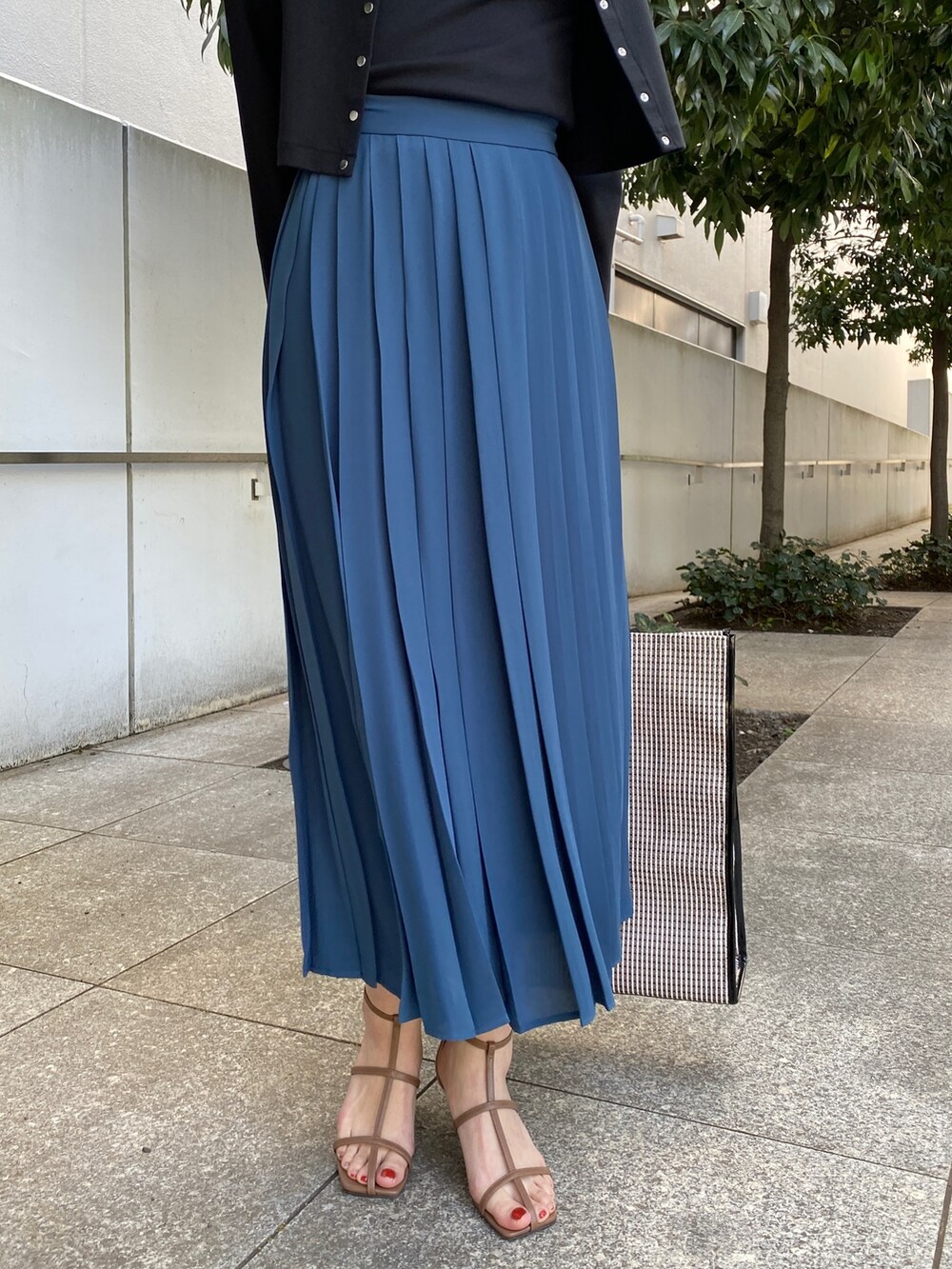 ブルー系のスカート、ブラウン系のサンダル、ブラック系のトートバッグを着用したレディースの春コーディネートの6枚目の写真