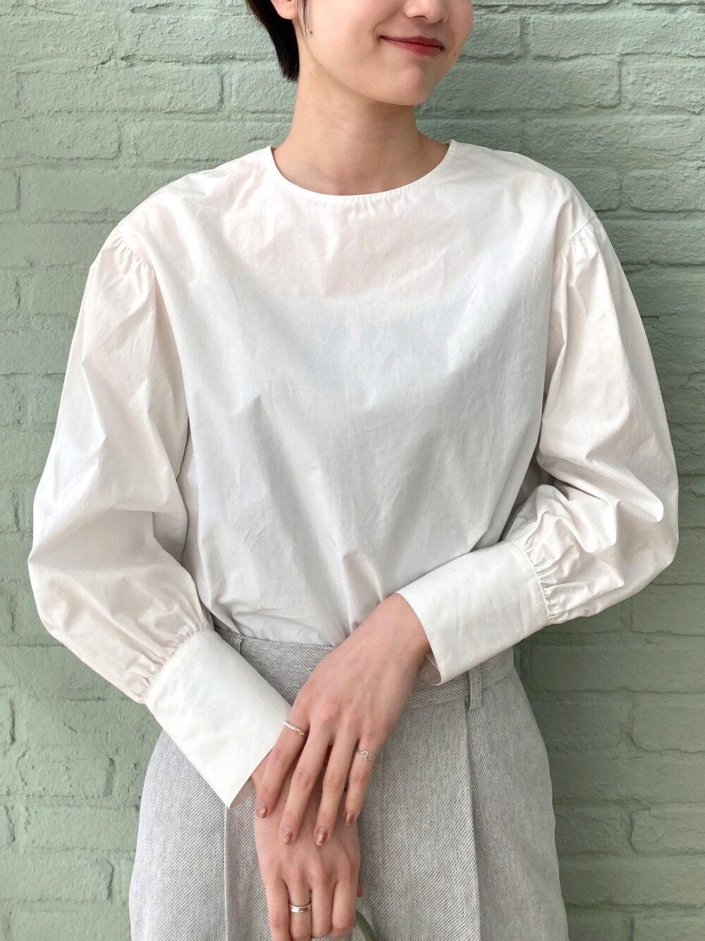 グリーン系のトートバッグ、ホワイト系のシャツ/ブラウス、ホワイト系のトレンチコートを着用したレディースの春コーディネートの3枚目の写真