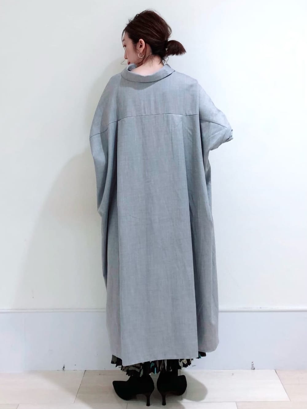 グレー系のワンピース、ブラック系のスカート、ブラック系のブーツを着用したレディースの秋コーディネートの3枚目の写真