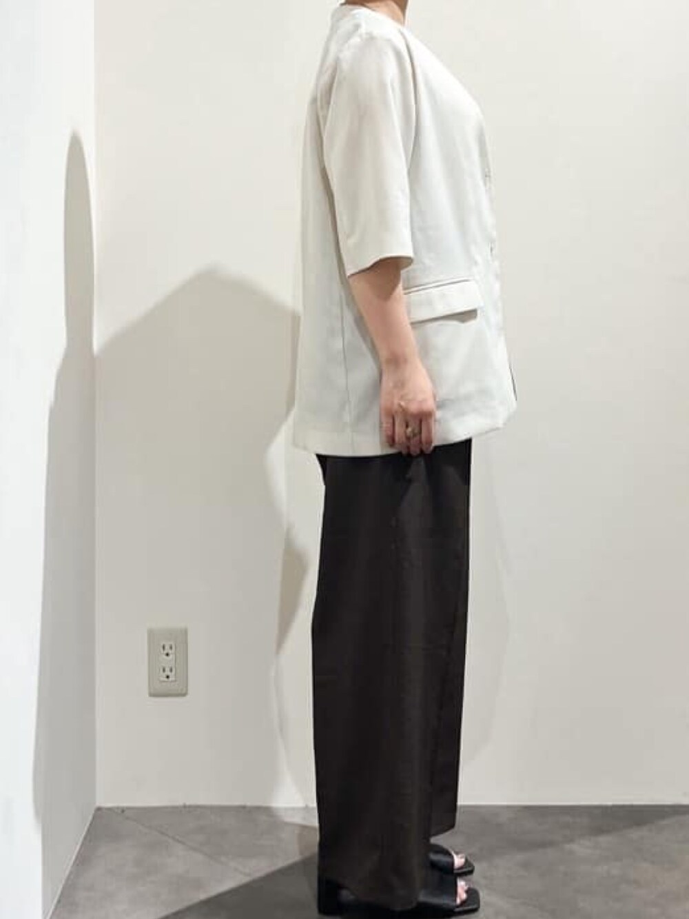 ベージュ系のノーカラージャケット、ベージュ系のニット/セーター、ブラック系のショルダーバッグを着用したレディースの夏コーディネートの3枚目の写真