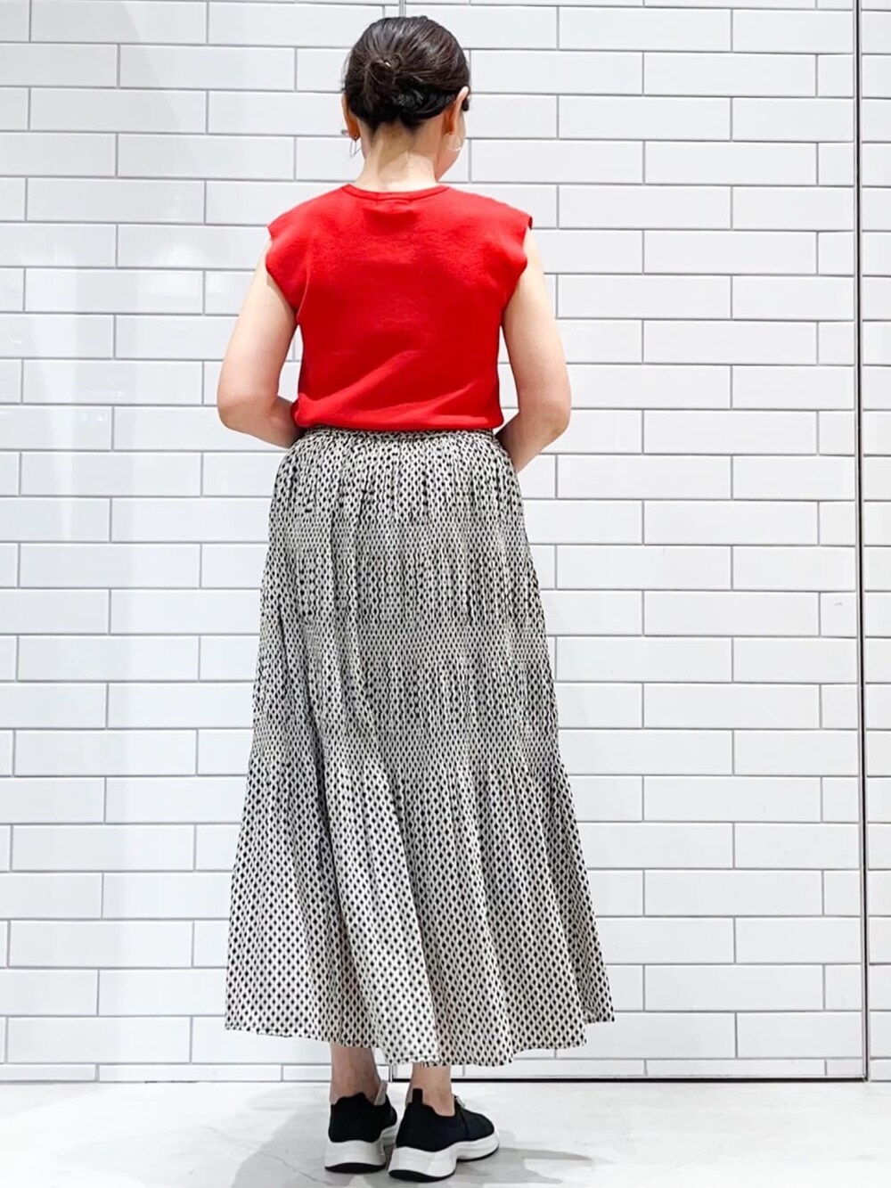 レッド系のニット/セーター、ブラック系のスカート、シルバー系のトートバッグを着用したレディースの夏コーディネートの2枚目の写真