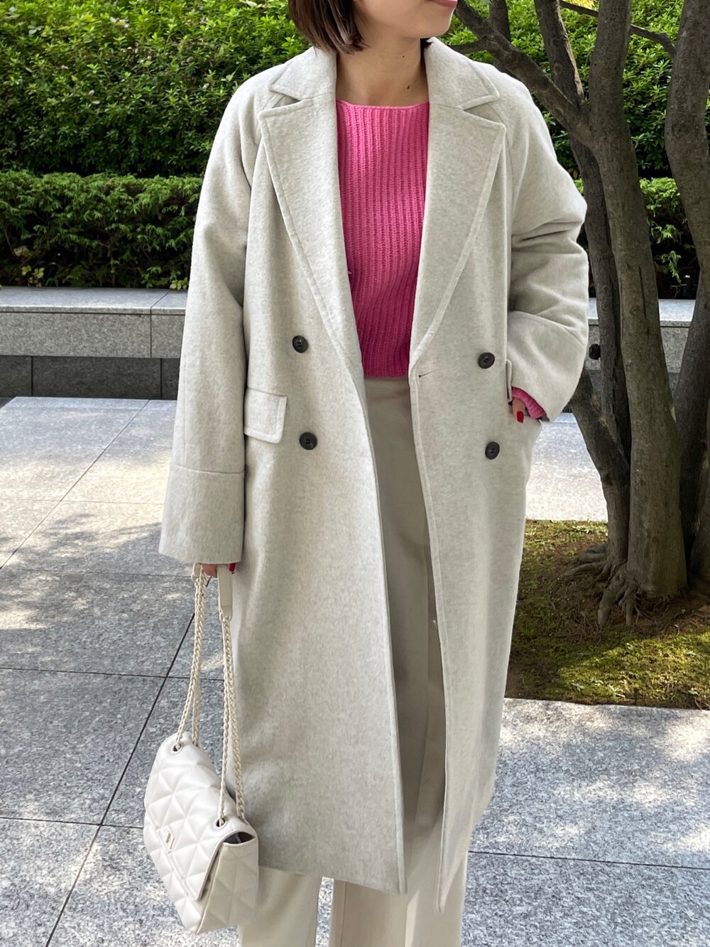 ピンク系のニット/セーター、ベージュ系のチェスターコート、ホワイト系のブーツを着用したレディースの秋コーディネートの2枚目の写真