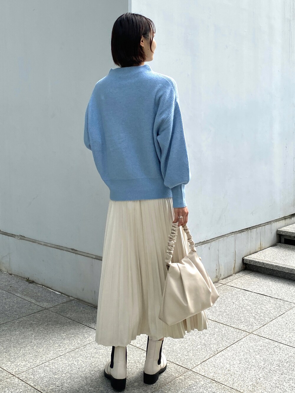 ブルー系のニット/セーター、ホワイト系のスカート、ホワイト系のハンドバッグを着用したレディースの秋コーディネートの3枚目の写真