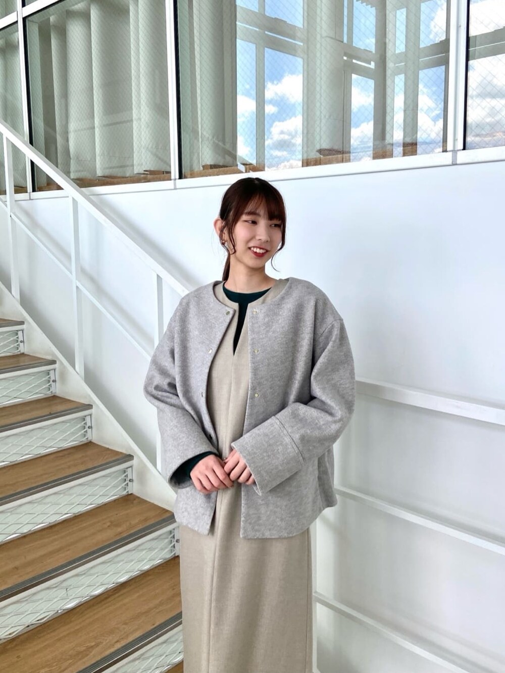 グレー系のノーカラーコート、ベージュ系のワンピース、ホワイト系のブーツを着用したレディースの秋コーディネートの5枚目の写真