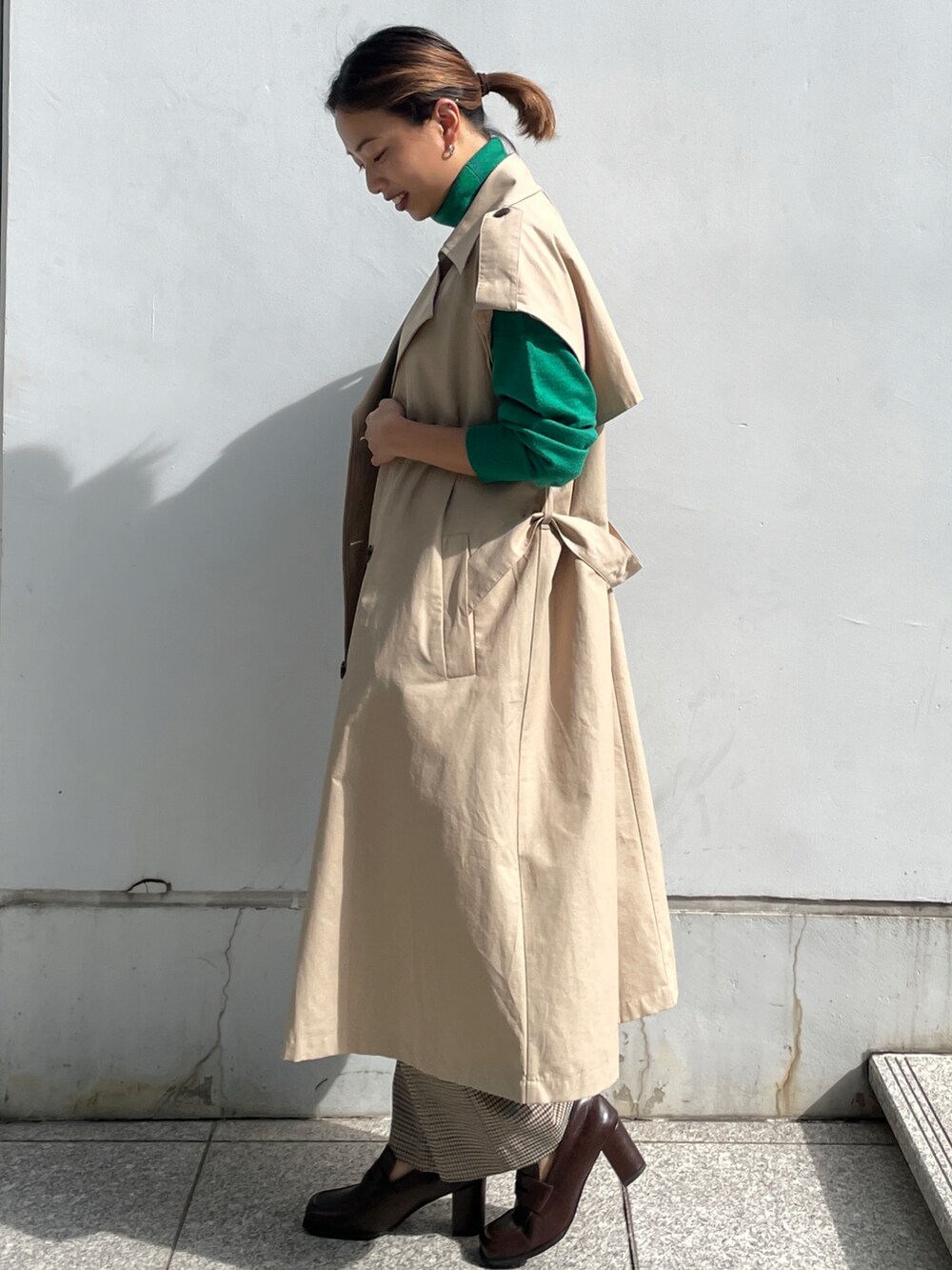 ベージュ系のトレンチコート、グリーン系のニット/セーター、ブラウン系のその他パンツを着用したレディースの秋コーディネートの4枚目の写真