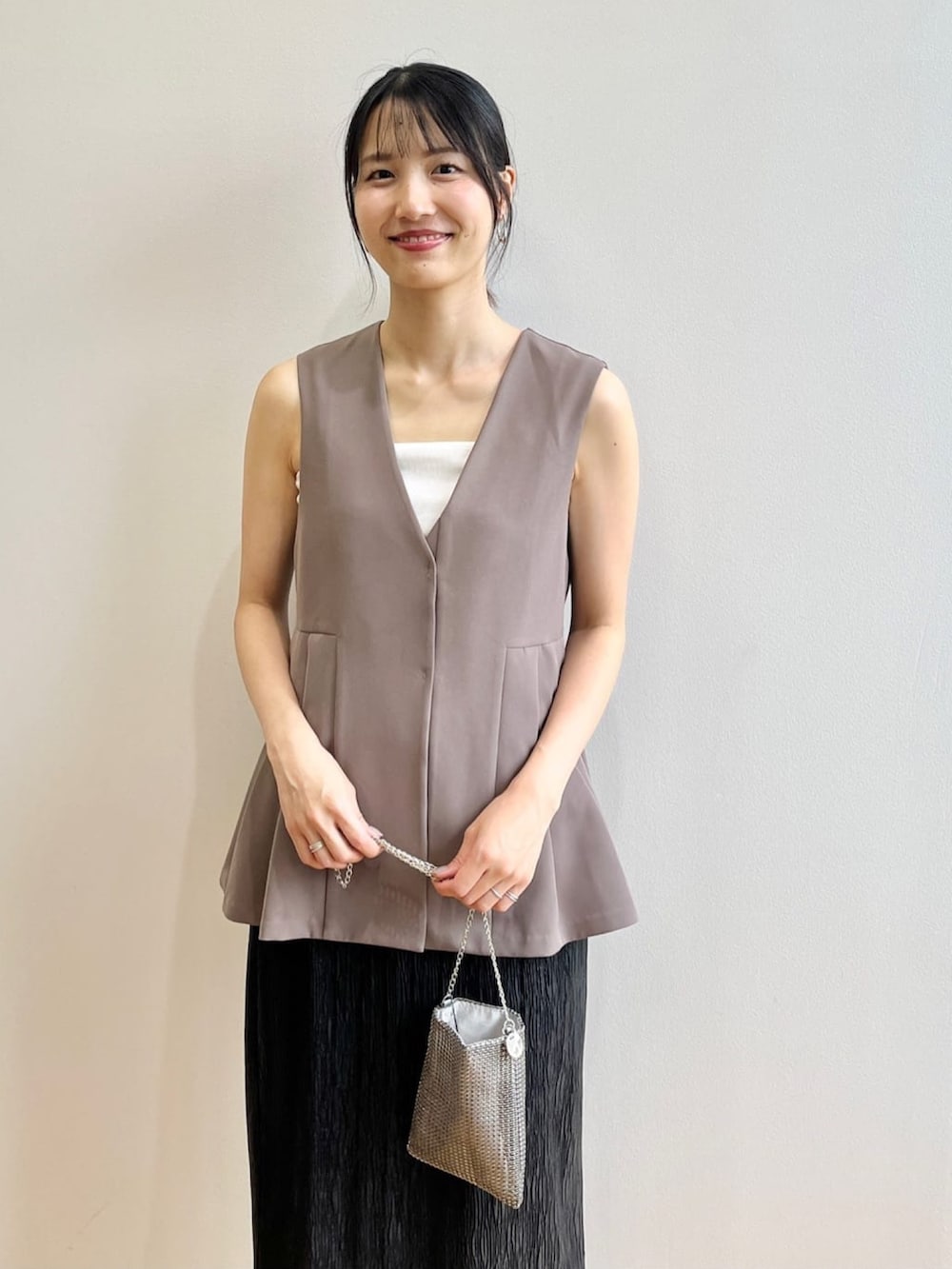 ホワイト系のタンクトップ、ホワイト系のサンダル、ブラウン系のベストを着用したレディースの夏コーディネートの4枚目の写真