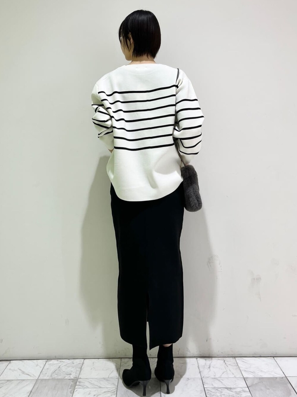 ホワイト系のニット/セーター、ブラック系のスカート、グレー系のショルダーバッグを着用したレディースの冬コーディネートの3枚目の写真