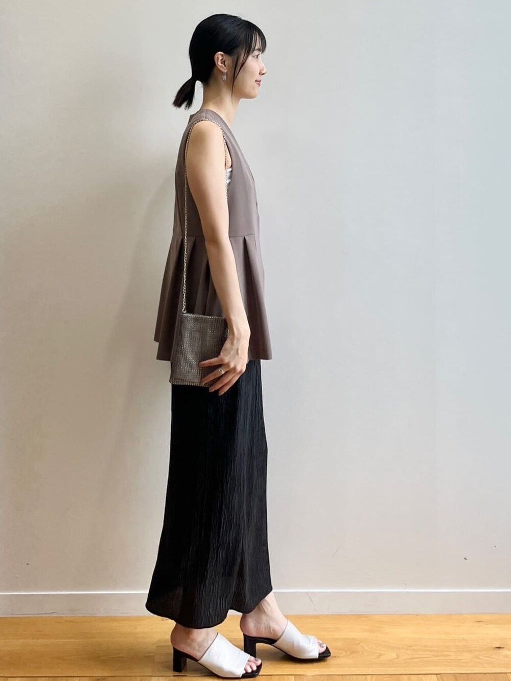 ホワイト系のタンクトップ、ホワイト系のサンダル、ブラウン系のベストを着用したレディースの夏コーディネートの2枚目の写真