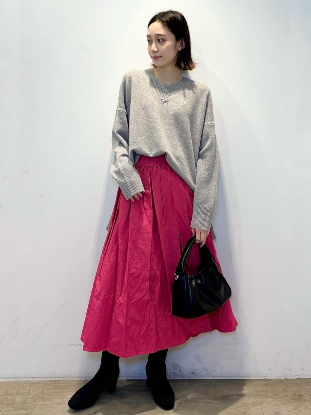 グレー系のニット/セーター、ピンク系のスカート、ブラック系のショルダーバッグを着用したレディースの冬コーディネートの5枚目の写真
