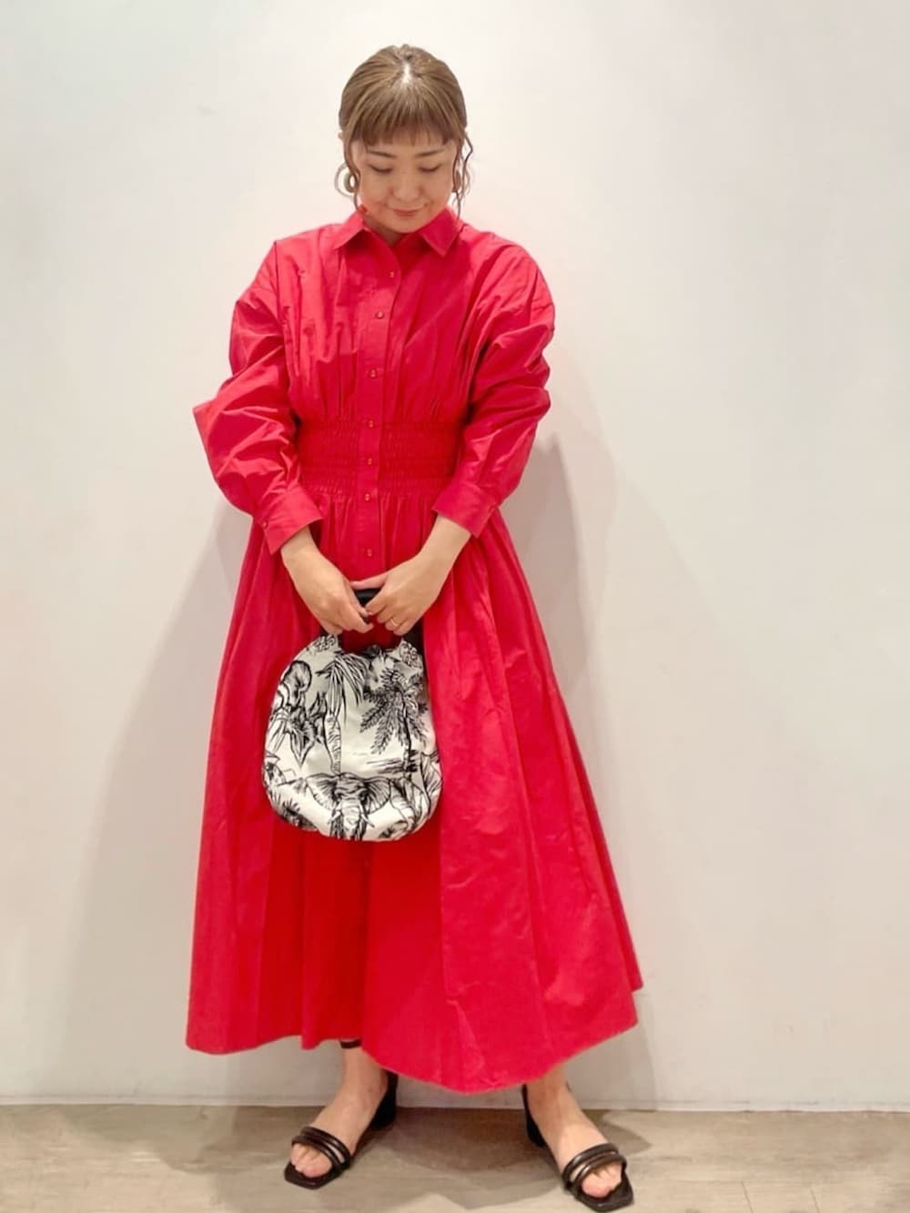 レッド系のワンピース、ホワイト系のハンドバッグ、ブラック系のサンダルを着用したレディースの春コーディネートの2枚目の写真