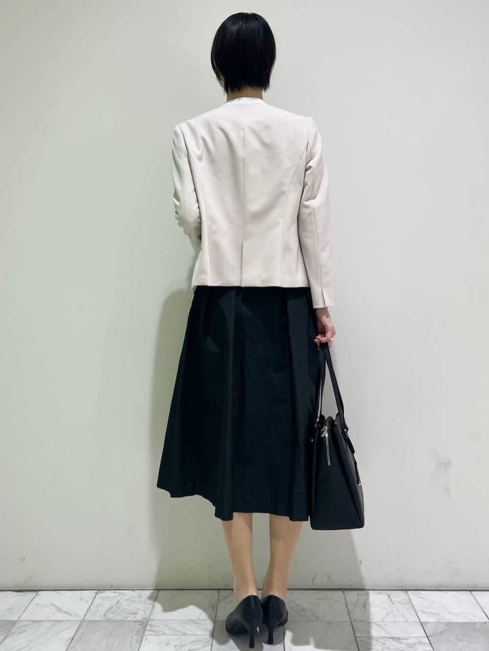 ベージュ系のノーカラージャケット、ブラック系のスカート、ブラック系のパンプスを着用したレディースの冬コーディネートの3枚目の写真