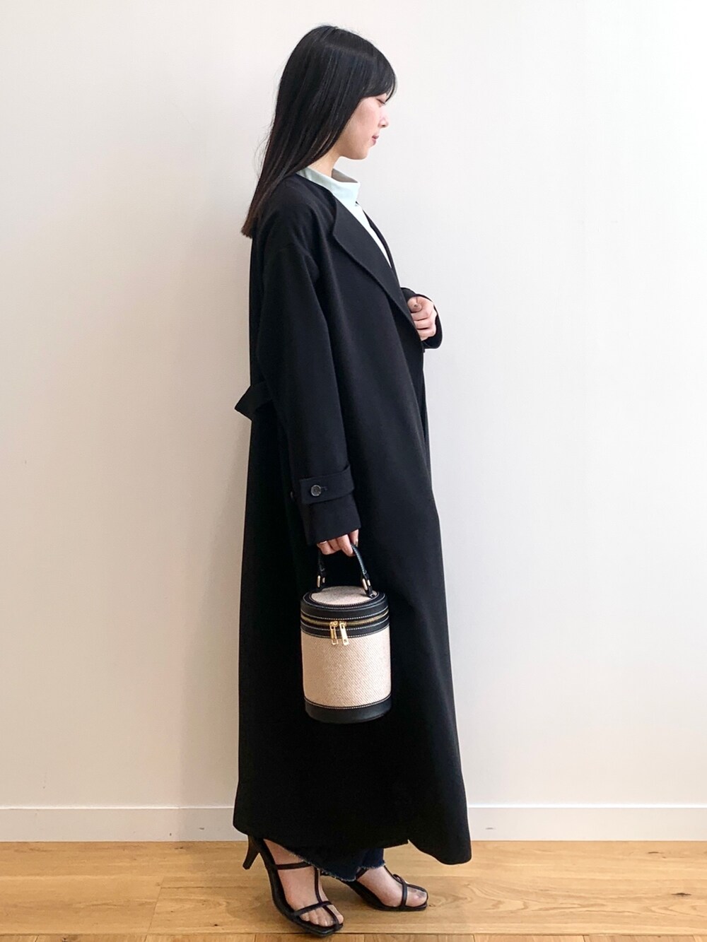 ブラック系のステンカラーコート、グリーン系のシャツ/ブラウス、ブルー系のデニムパンツを着用したレディースの春コーディネートの2枚目の写真