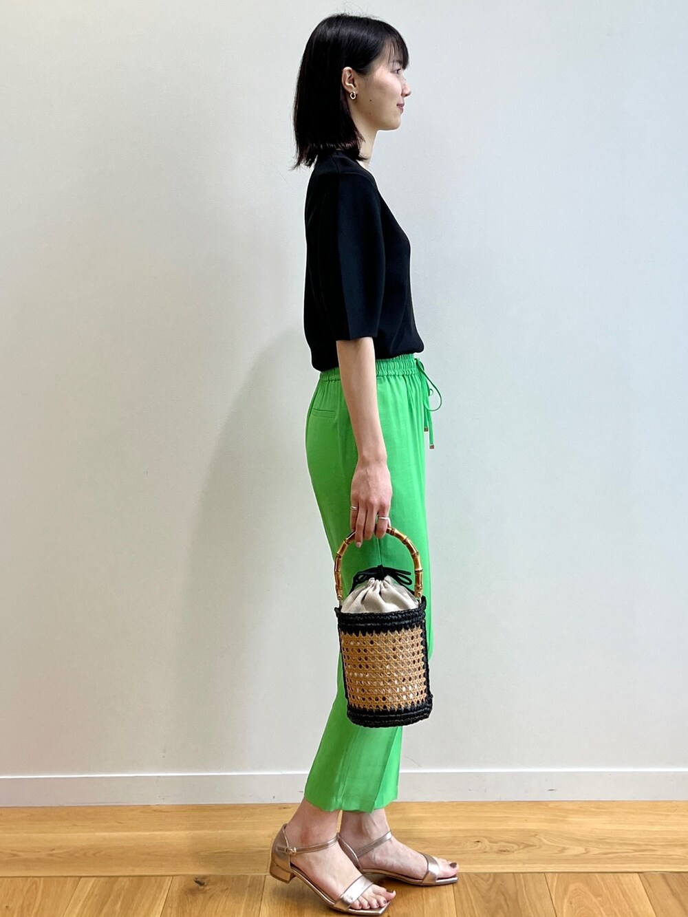 ブラック系のニット/セーター、ゴールド系のサンダル、ブラック系のトートバッグを着用したレディースの春コーディネートの2枚目の写真