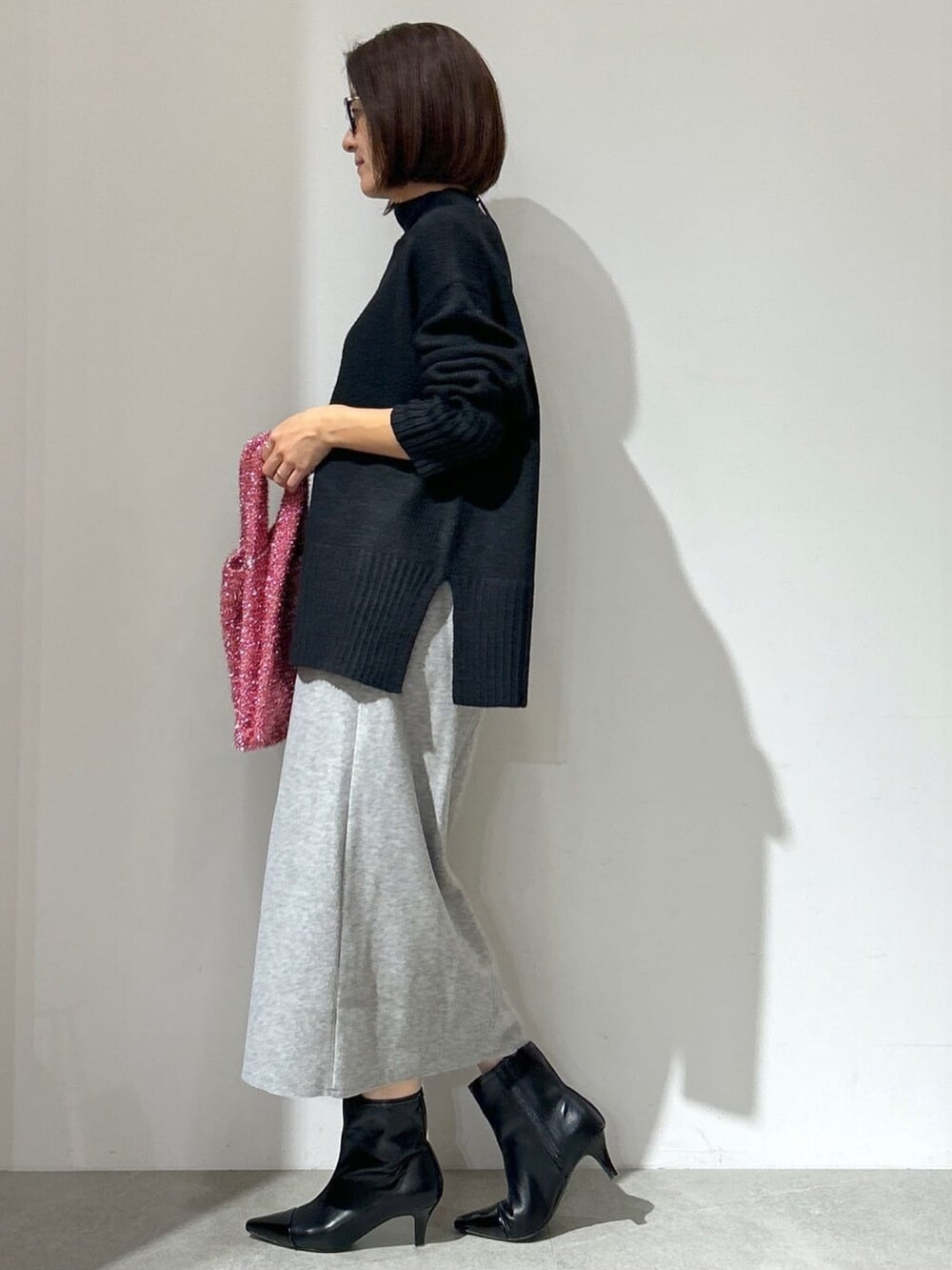 ホワイト系のノーカラーコート、グレー系のスカート、ブラック系のショルダーバッグを着用したレディースの秋コーディネートの6枚目の写真