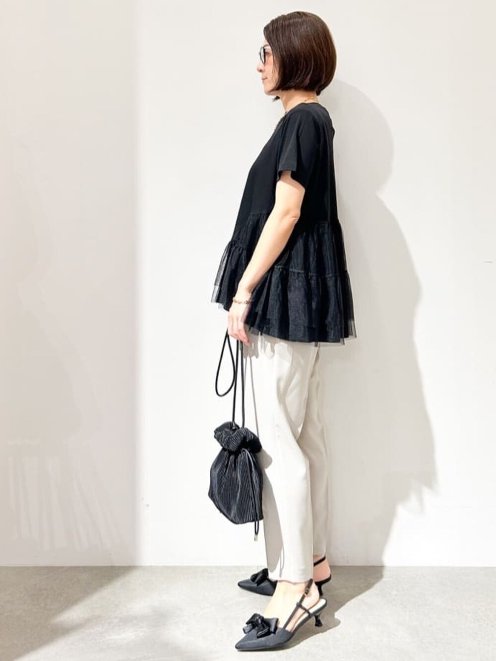 グレー系のその他パンツ、ブラック系のショルダーバッグ、ブラック系のパンプスを着用したレディースの春コーディネートの2枚目の写真
