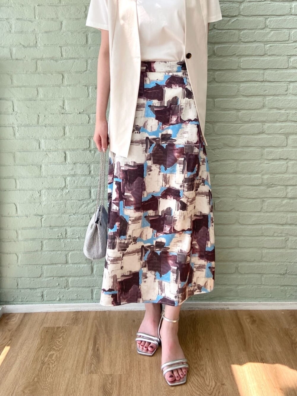 ベージュ系のベスト、ホワイト系のTシャツ/カットソー、レッド系のスカートを着用したレディースの夏コーディネートの9枚目の写真