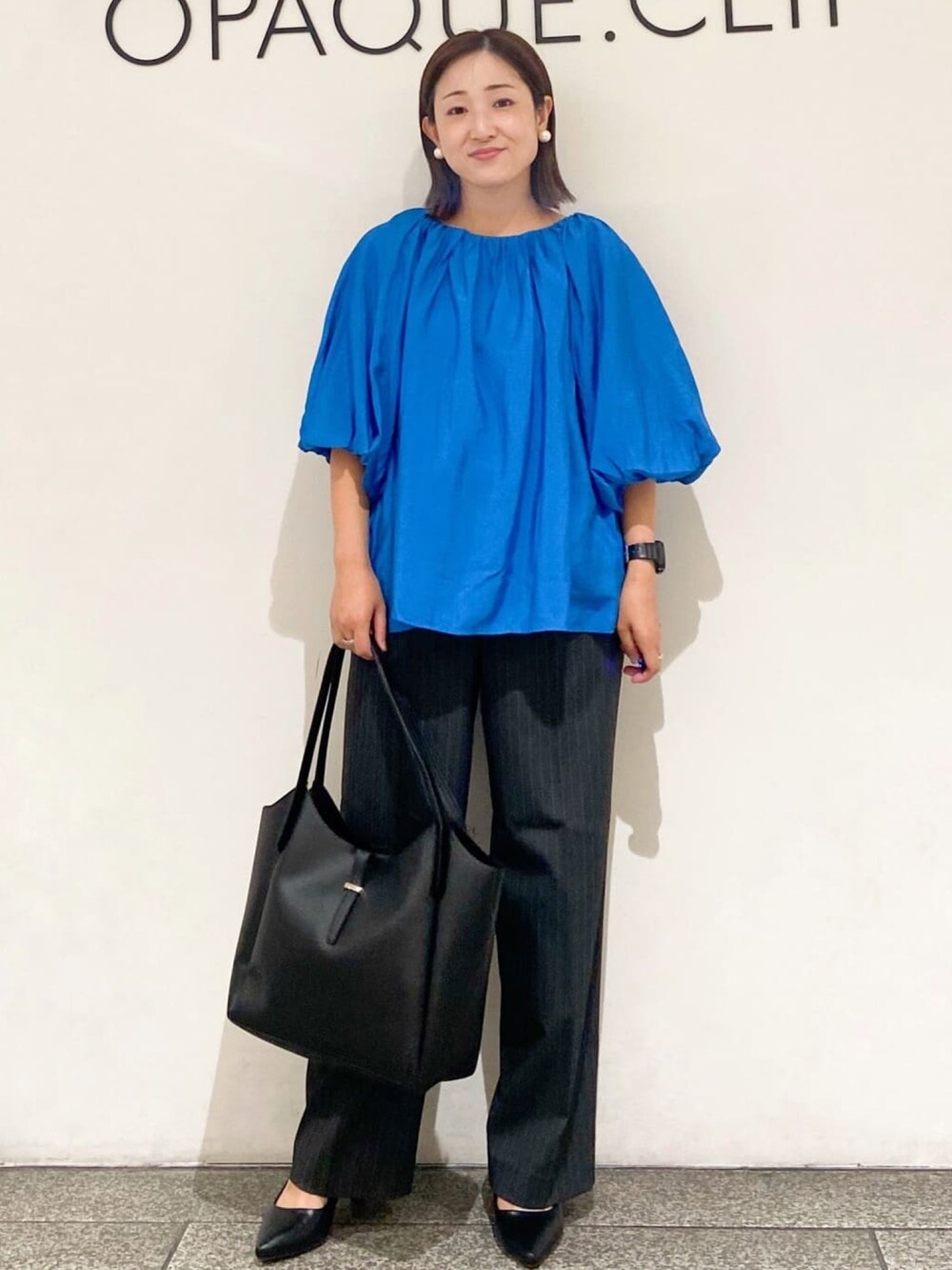 ブルー系のシャツ/ブラウス、グレー系のその他パンツ、ブラック系のトートバッグを着用したレディースの夏コーディネートの3枚目の写真