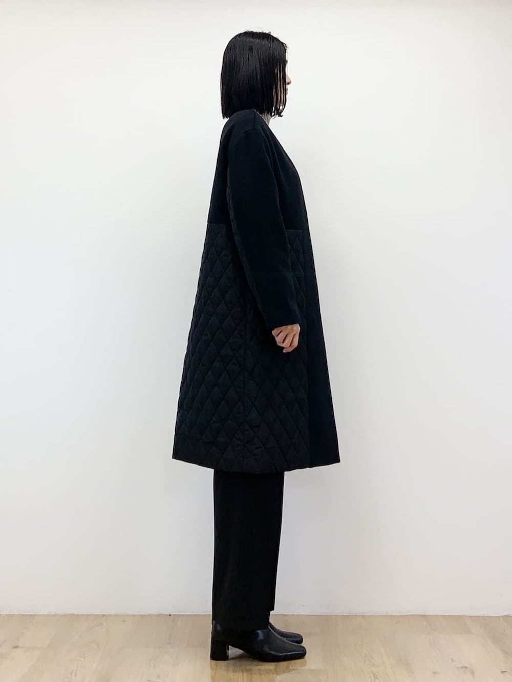 ブラック系のノーカラーコート、ベージュ系のニット/セーター、ブラック系のその他パンツを着用したレディースの秋コーディネートの3枚目の写真