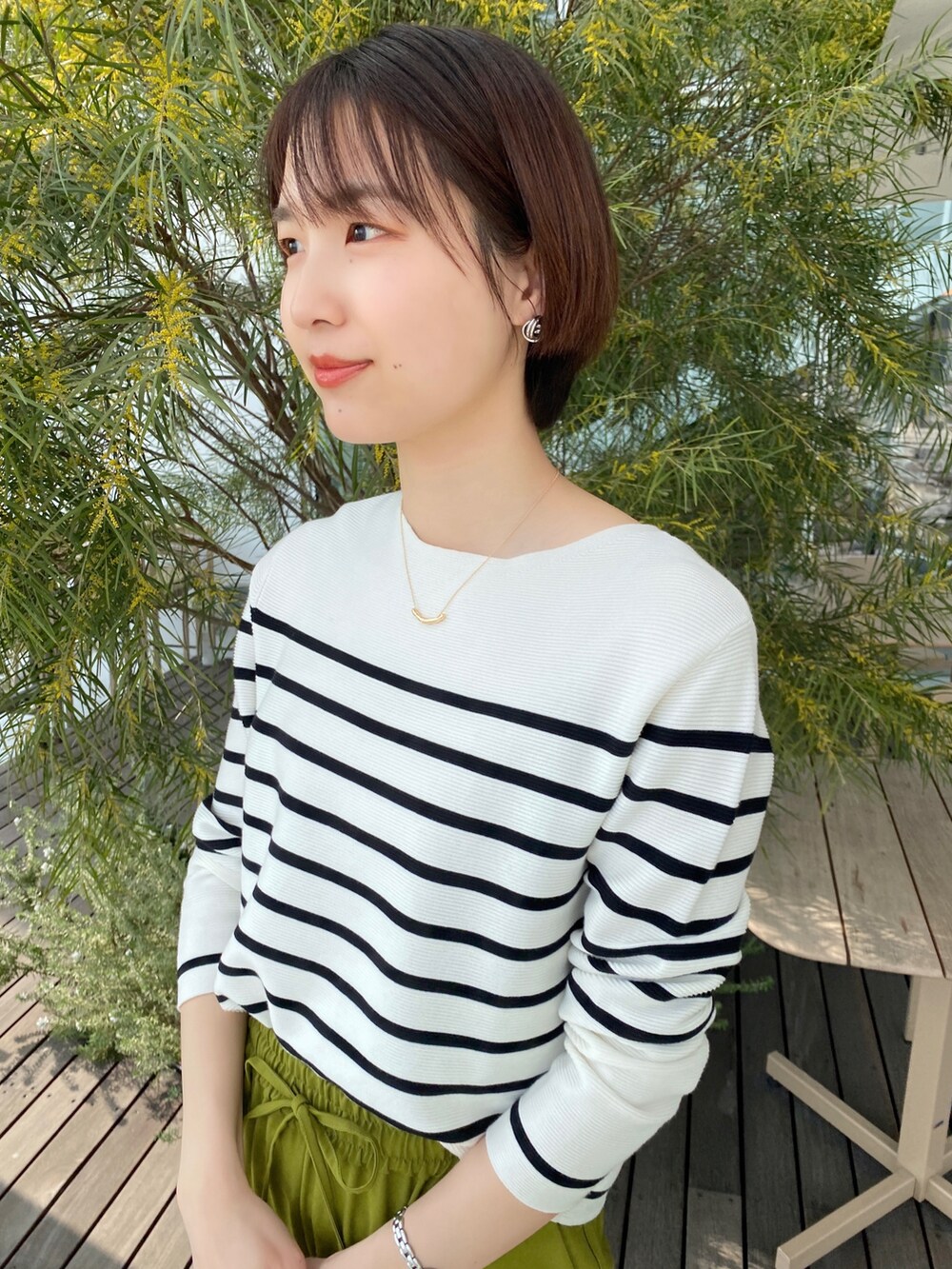 ホワイト系のニット/セーター、グリーン系のその他パンツ、ベージュ系のショルダーバッグを着用したレディースの春コーディネートの2枚目の写真