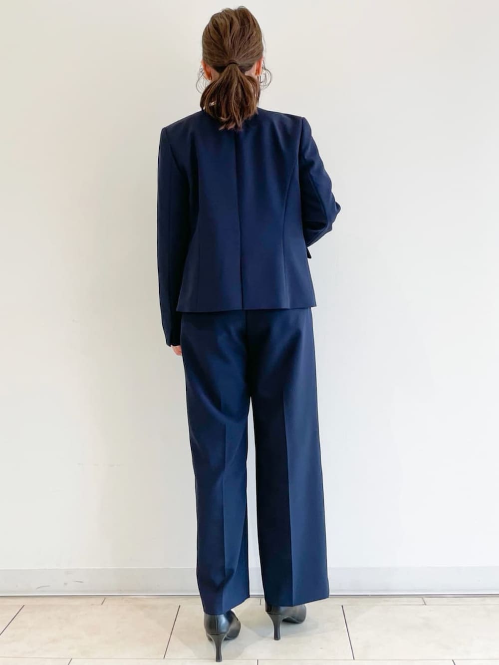 ブラック系のパンプス、ベージュ系のトレンチコート、ブルー系のスーツパンツを着用したレディースの春コーディネートの4枚目の写真