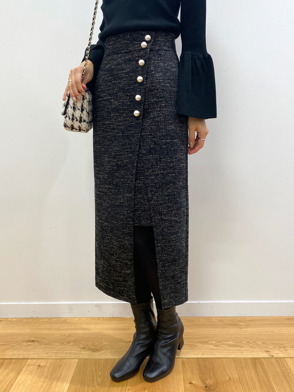 ブラック系のニット/セーター、ブラック系のブーツ、ブラック系のショルダーバッグを着用したレディースの冬コーディネートの5枚目の写真