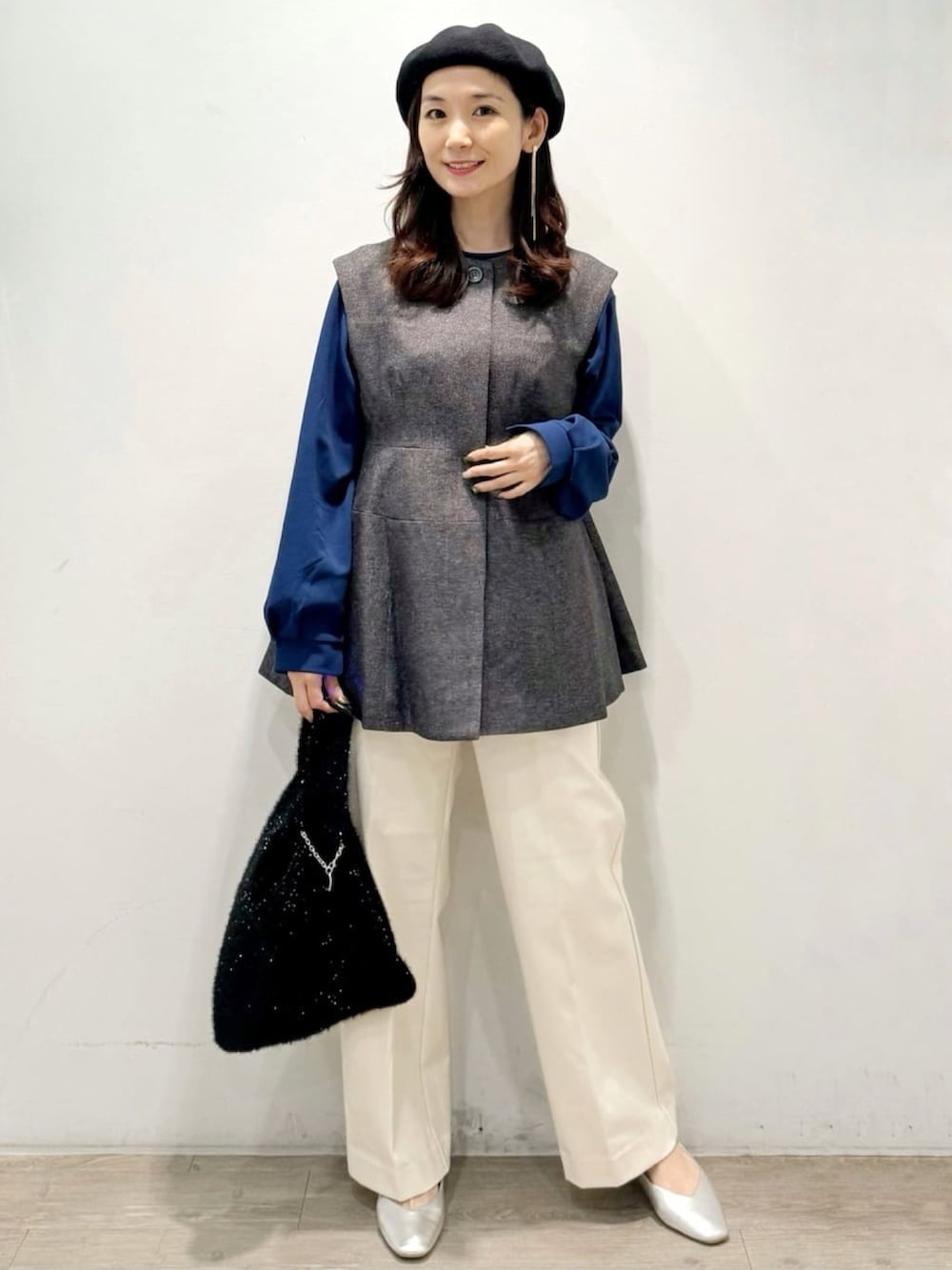 ブラック系のハンドバッグ、ホワイト系のその他パンツ、グレー系のベストを着用したレディースの秋コーディネートの2枚目の写真