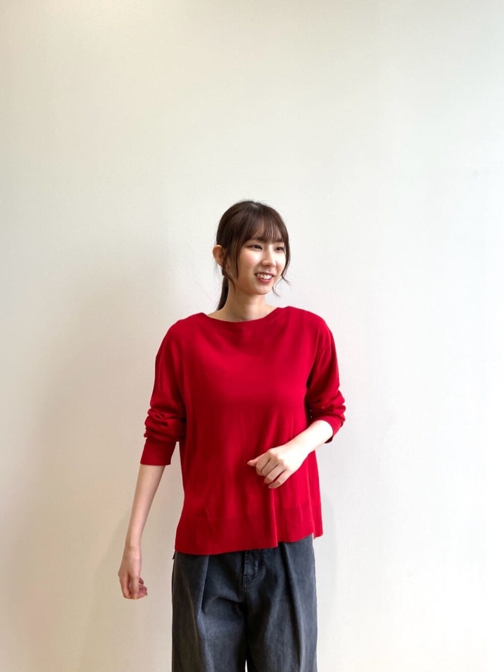 レッド系のニット/セーター、ブラック系のデニムパンツ、ブラック系のパンプスを着用したレディースの秋コーディネートの5枚目の写真