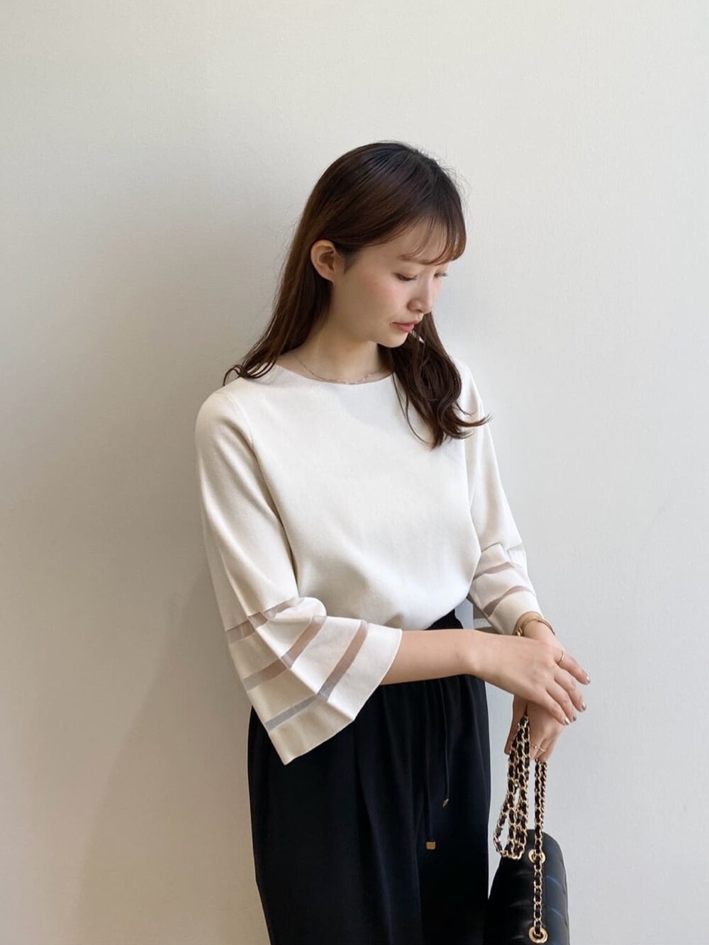 ホワイト系のニット/セーター、ブラック系のその他パンツ、ブラック系のショルダーバッグを着用したレディースの春コーディネートの7枚目の写真