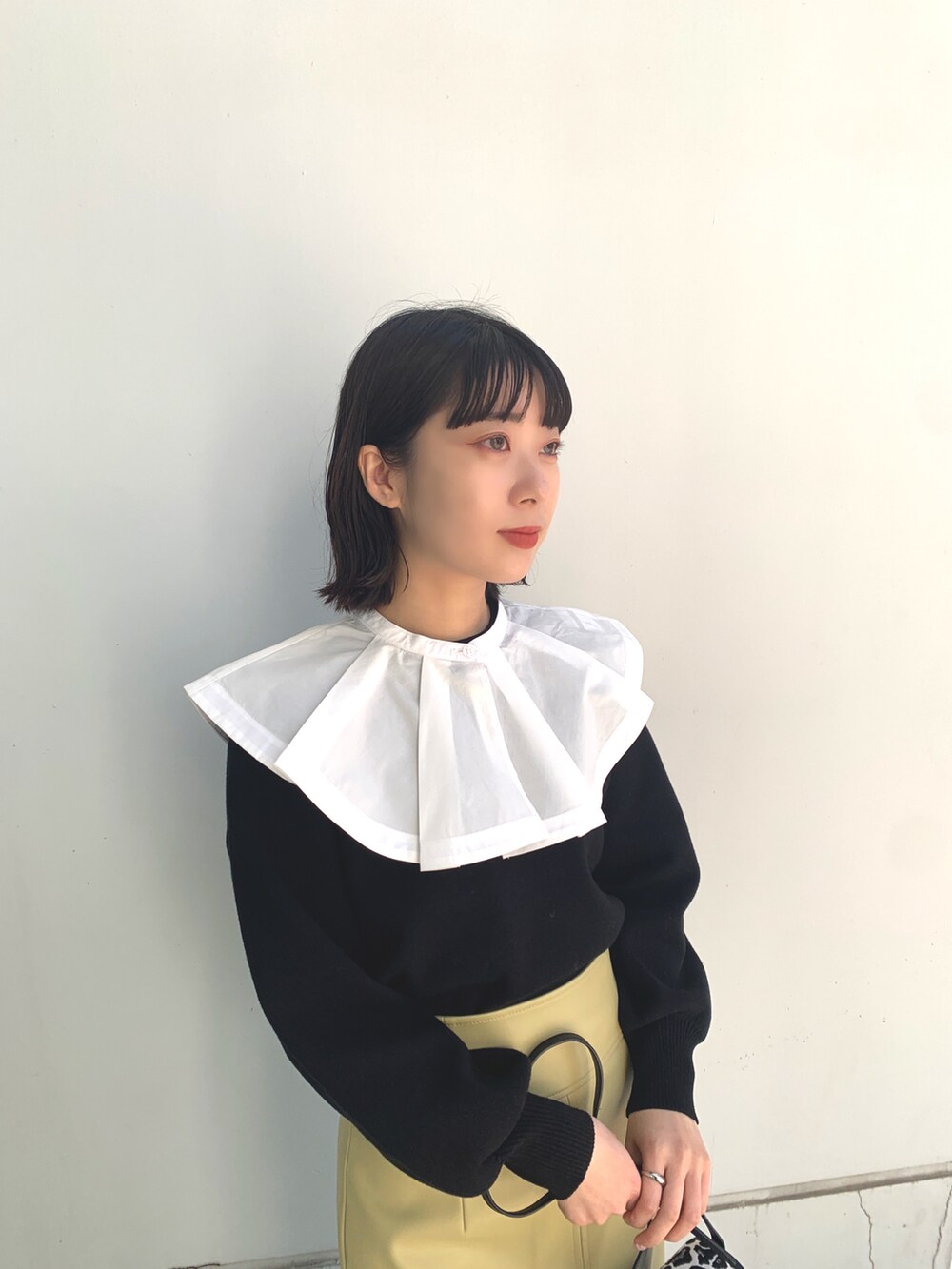 ブラック系のドレスシューズ、イエロー系のスカート、ブラック系のニット/セーターを着用したレディースの春コーディネートの3枚目の写真