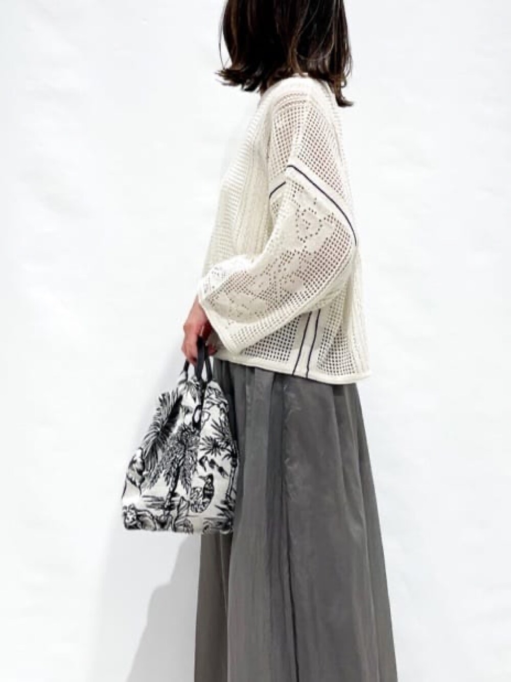 ホワイト系のニット/セーター、グレー系のスカート、ホワイト系のハンドバッグを着用したレディースの春コーディネートの8枚目の写真