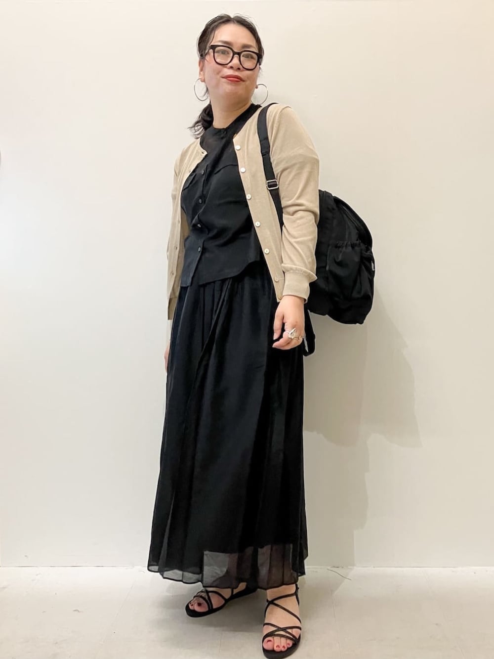 ベージュ系のカーディガン/ボレロ、ブラック系のシャツ/ブラウス、ブラック系のスカートを着用したレディースの春コーディネートの2枚目の写真