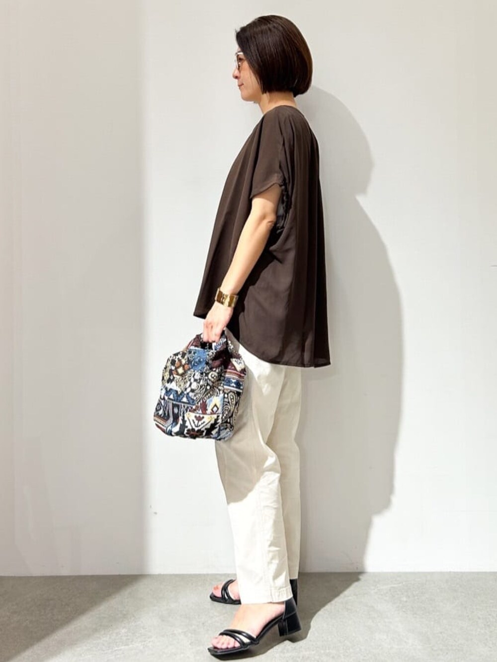 ブラウン系のTシャツ/カットソー、ブルー系のハンドバッグ、ブラック系のサンダルを着用したレディースの夏コーディネートの2枚目の写真